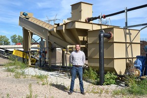 Jason Ziss, manager of business development at Kurtz Bros., stands next to the company's screw dewatering plant that receives Cuyahoga River-harvested sediment. In another shot, Ziss shows the processed sand that emerges from the plant.